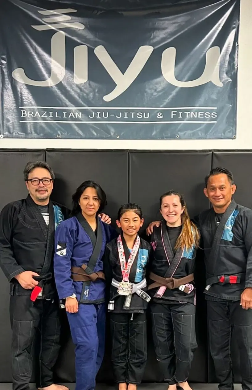 Jiyu coaches with a young student and her new medal under the Jiyu banner