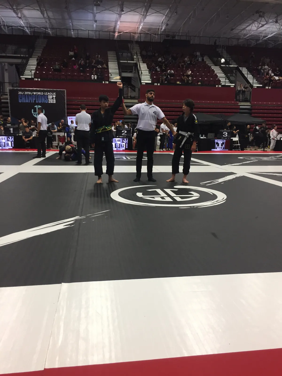 A referee raising a Jiyu competitor's hand after a match at the Jiu Jitsu World League Champions Cup